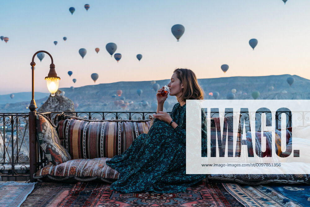 Woman drinking early morning tea with hot air balloons in Cappadocia Go¶reme, NevAÂüehir, Turkey ,model released, Symbolfoto CR_SEAK200116B-287292-01