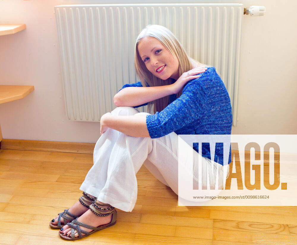 A young woman sitting in front of a radiator in winter and freezing, MR Yes McPBBO McPBBO