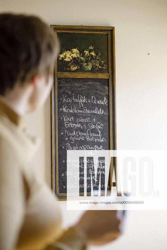 Symbol photo on the subject of cooking at home A woman looks at a chalkboard on which a weekly plan with meals has been written Berlin, 26 03 2020 Berlin Germany