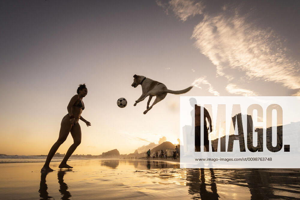 IMAGO Creative: Sommer Sport - Strand Couple playing soccer with dog on the water front in Copacabana Beach Rio de Janeiro, RJ, Brazil ,editorial use only CR_GNUJ200326C-328399-01