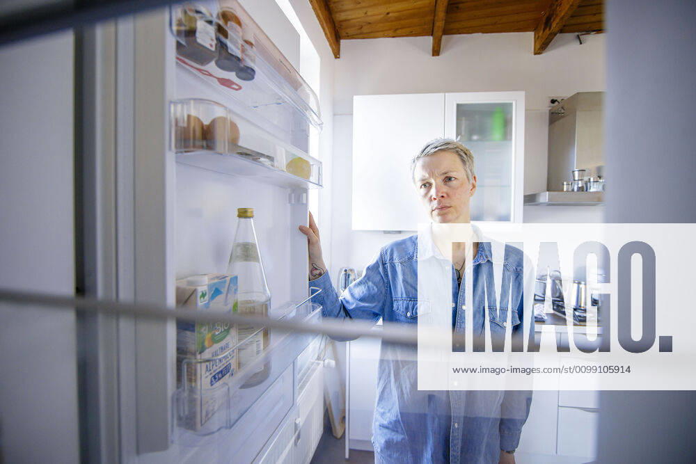 Symbolic image on the subject of poverty A woman looks depressed into an almost empty fridge Berlin, 05 04 2020 During the crisis about the corona virus, COVID 19, SARS CoV 2 many people are on short-time work and have to limit their financial resources This affects for example the household budget from Berlin Germany
