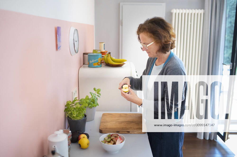 Woman standing in the kitchen cutting an apple Bonn Germany