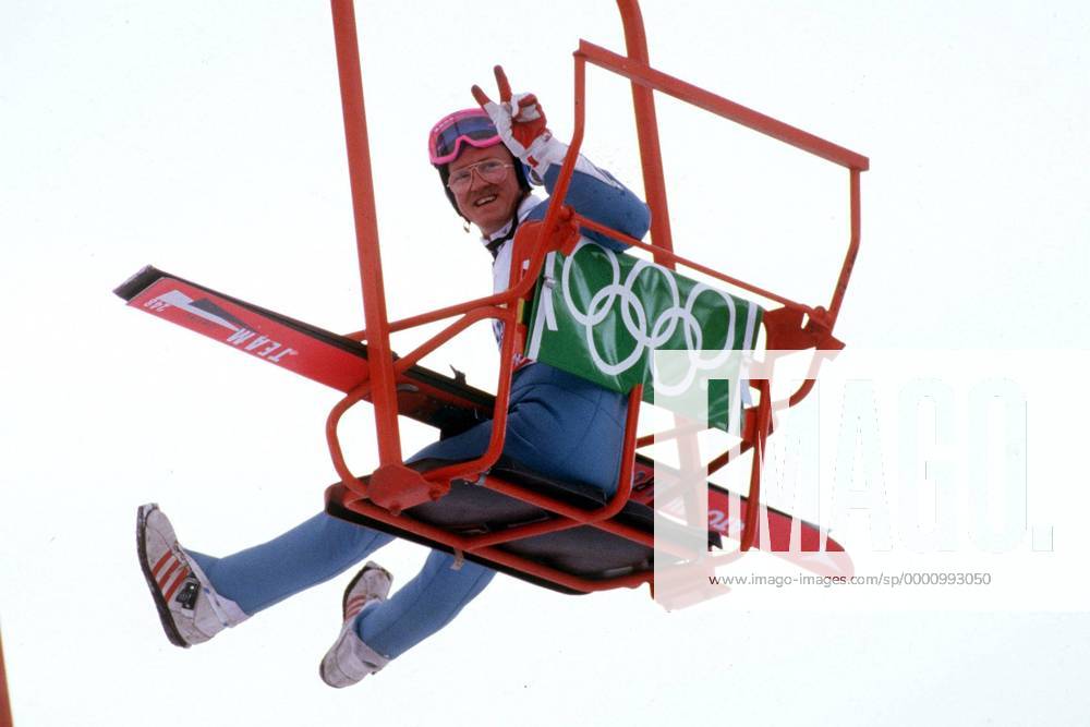 Michael Edwards (Großbritannien) alias Eddie the Eagle grüßt mit dem Peace-Zeichen aus einem Sessellift Der erste Brite, bei einem olympischen Skispringen war mehr Publikumsliebling als Sieganwärter bei den Olympischen Spielen von Calgary 1988 und wurde sogar in einer Rede auf der Abschlussfeier erwähnt. Skispringen OS Winter Herren Olympische Winterspiele 1988, Olympia, Olympiade, Spiele, Skisprung, Ski Nordisch, Nordischer Einzelbild Calgary