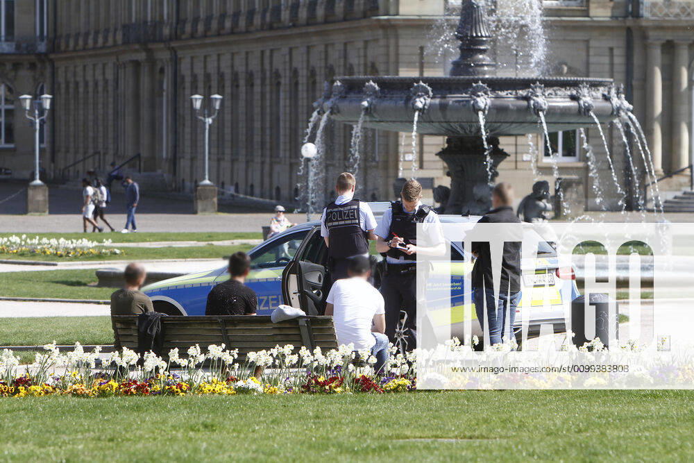 A police patrol of the Baden Württemberg state police checks the personal data of passers-by who were sitting on a bench on the Schlossplatz and thus had not kept the prescribed minimum distance in the city centre of Stuttgart, Baden Württemberg, Bavaria, Germany
