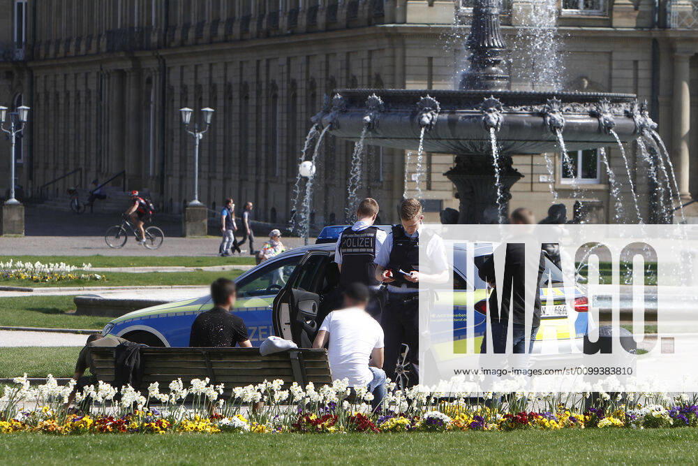 A police patrol of the Baden Württemberg state police checks the personal data of passers-by who were sitting on a bench on the Schlossplatz in a threesome and thus had not kept the prescribed minimum distance in the city centre of Stuttgart, Baden Württemberg, Bavaria, Germany