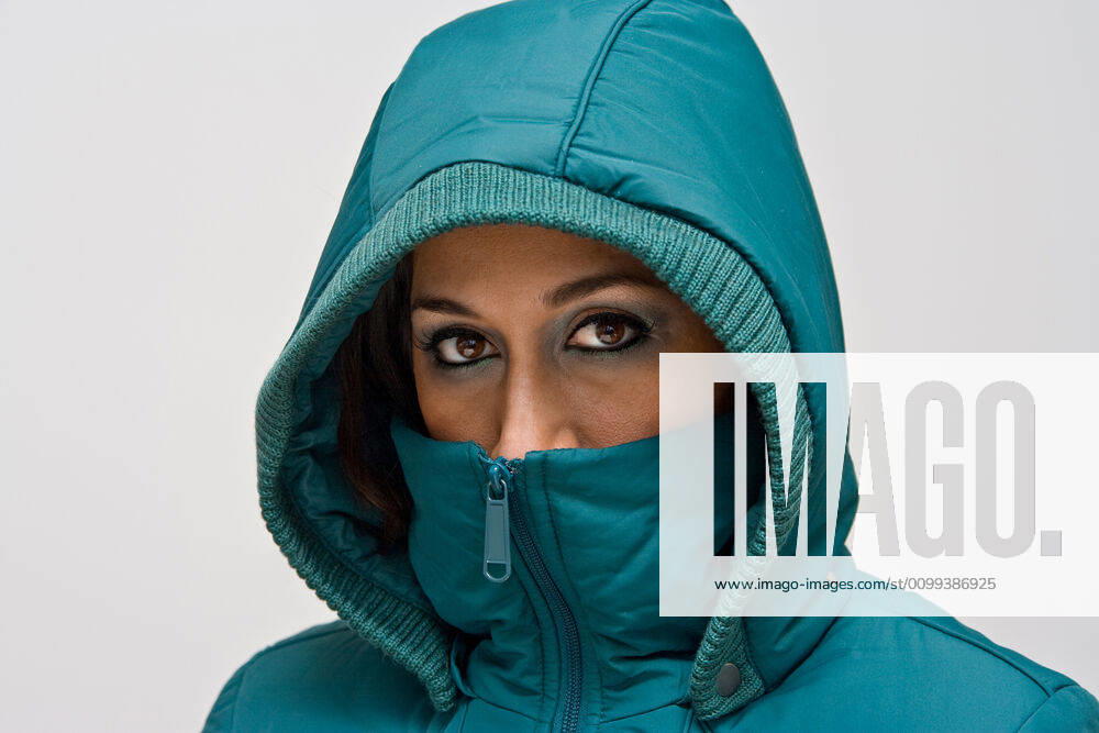 Young woman with green hood A young woman wearing a green winter coat using the hood to cover her head so that only her eyes are visible, isolated on white