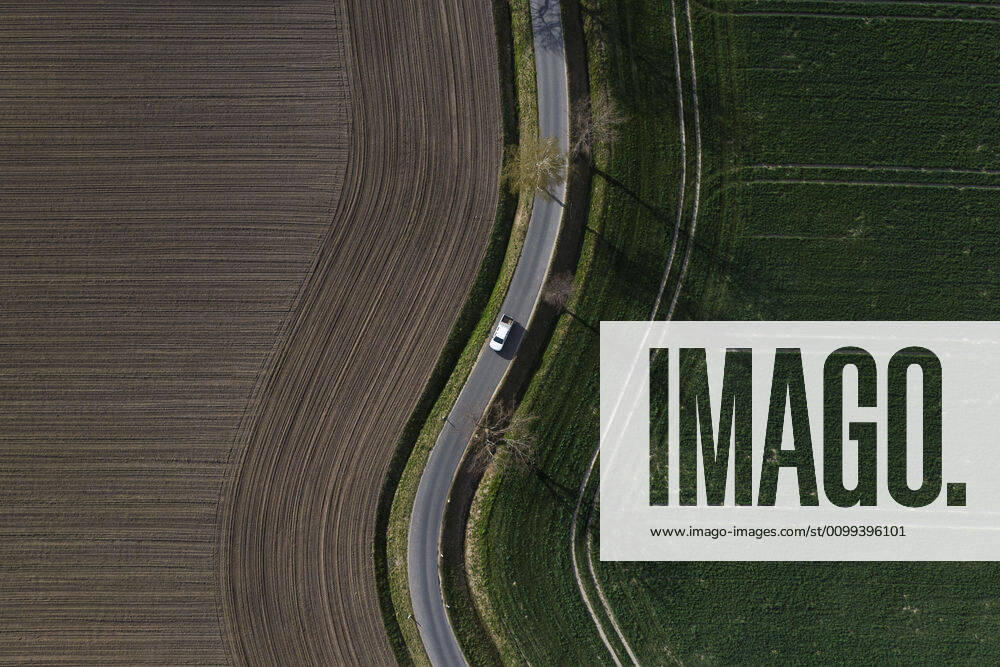 A car driving along a winding road between two fields, taken in Wiesa, 14 04 2020 Wiesa Germany