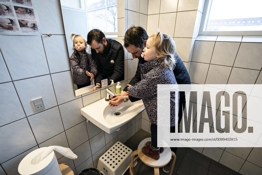 The nursery DUI in Aalborg opens again for the institutions children, Wednesday morning, April 15, 2020 Solvej wash hands with his father Due to the corona crisis, the nursery has been closed, and after the nursery has been changed inside and outside the children and the adult educators can hold distance and washing hands, Aalborg Jutland Denmark,