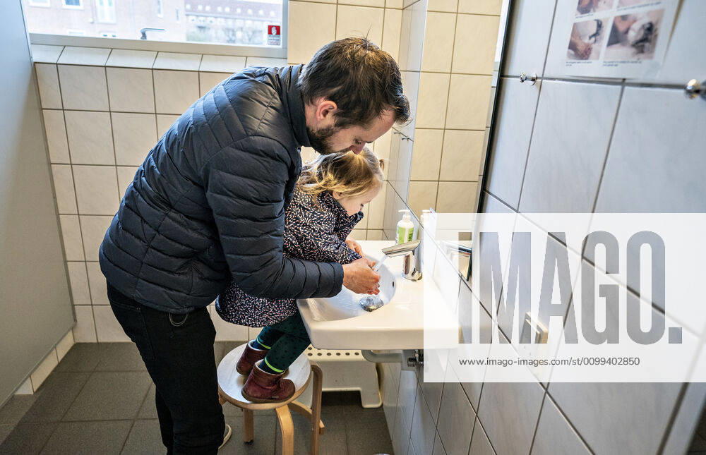 The nursery DUI in Aalborg opens again for the institutions children, Wednesday morning, April 15, 2020 Solvej wash hands with his father Due to the corona crisis, the nursery has been closed, and after the nursery has been changed inside and outside the children and the adult educators can hold distance and washing hands, Aalborg Jutland Denmark,