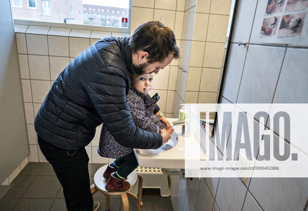 The nursery DUI in Aalborg opens again for the institutions children, Wednesday morning, April 15, 2020 Solvej wash hands with his father Due to the corona crisis, the nursery has been closed, and after the nursery has been changed inside and outside the children and the adult educators can hold distance and washing hands, Aalborg Jutland Denmark,