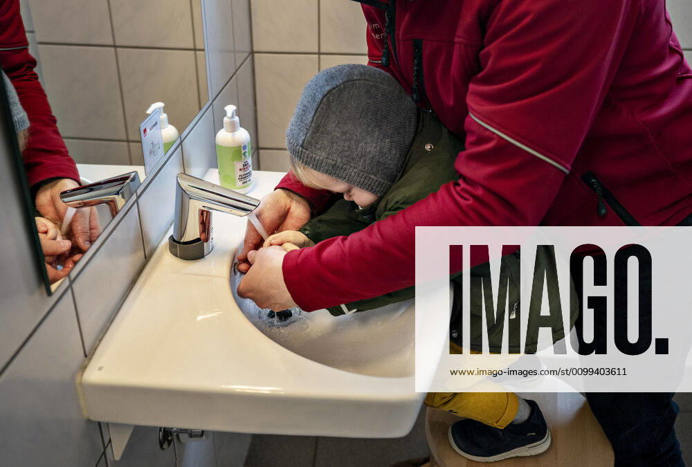 The nursery DUI in Aalborg opens again for the institutions children, Wednesday morning, April 15, 2020 Here, Aksel and his father wash their hands as the first on arrival Due to the corona crisis, the nursery has been closed and after the nursery has been changed inside and outside the children can and the adult educators keep away and wash hands, Aalborg Jutland Denmark,