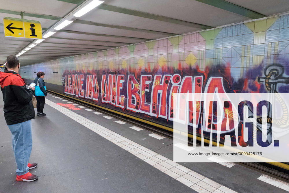 People can be seen next to a large graffiti by the artist group 1UP with the text Leave no one behind on the wall of the underground station KurfuerstenstraoÅ¸e in Berlin. The hashtag used is recalling the debate about the politics, practices and events surrounding the European border regime and about migration movements and is often used by groups advocating humanitarian rights for refugees. - ZUMAs172 20200416_zap_s172_003