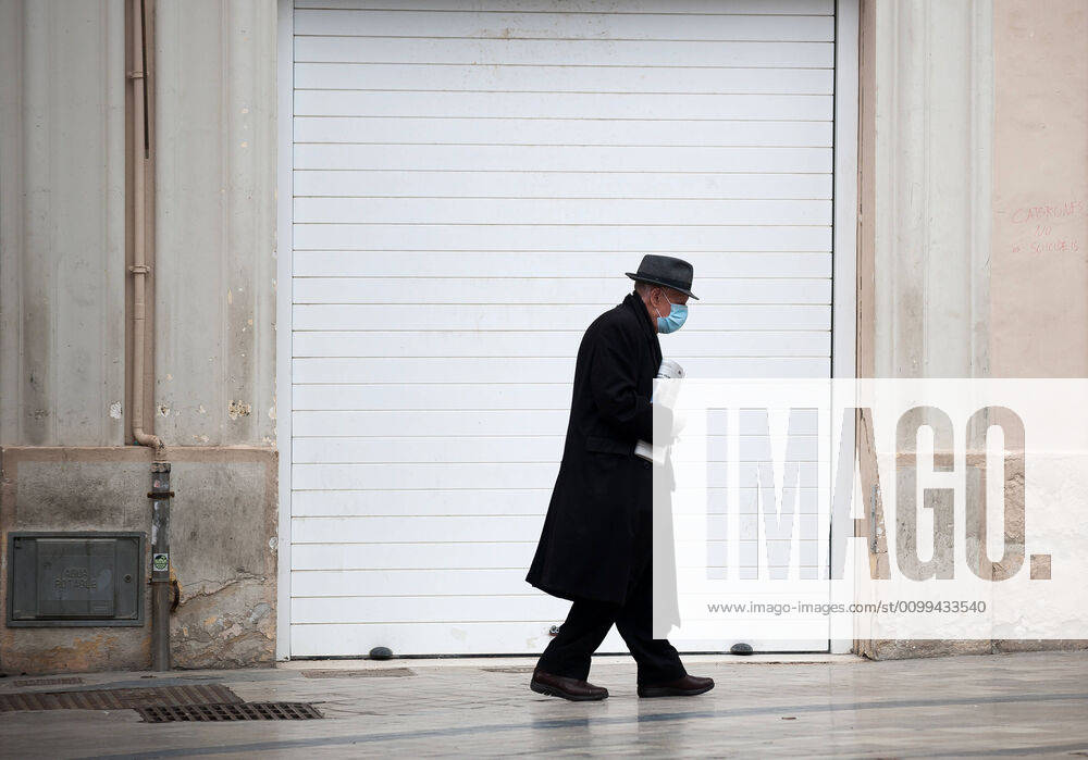 An elderly man wearing a face mask walking past a closed store during the covid-19 crisis..Following the confinement decreed by the Spanish government and will extended until 10th May, people are confinement in their homes causing an exceptional situation of unusual urban scenes such as empty streets. Malaga Spain - ZUMAs197 20200416_zaa_s197_049