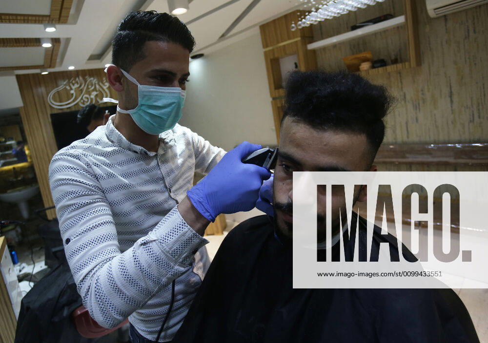 Daily Life at Barber in Southern Gaza Strip, Palestine amid Coronavirus Outbreak - 16 April 2020. A Palestinian barber wearing a face mask and a medical glove with his hand as a precautionary measure against Coronavirus (COVID-19), sterilizes his tools before cutting the customer s hair in Khan Yunis, southern Gaza Strip, Palestine, April 16, 2020. (Photo by Yousef Masoud INA Photo Agency imago images)