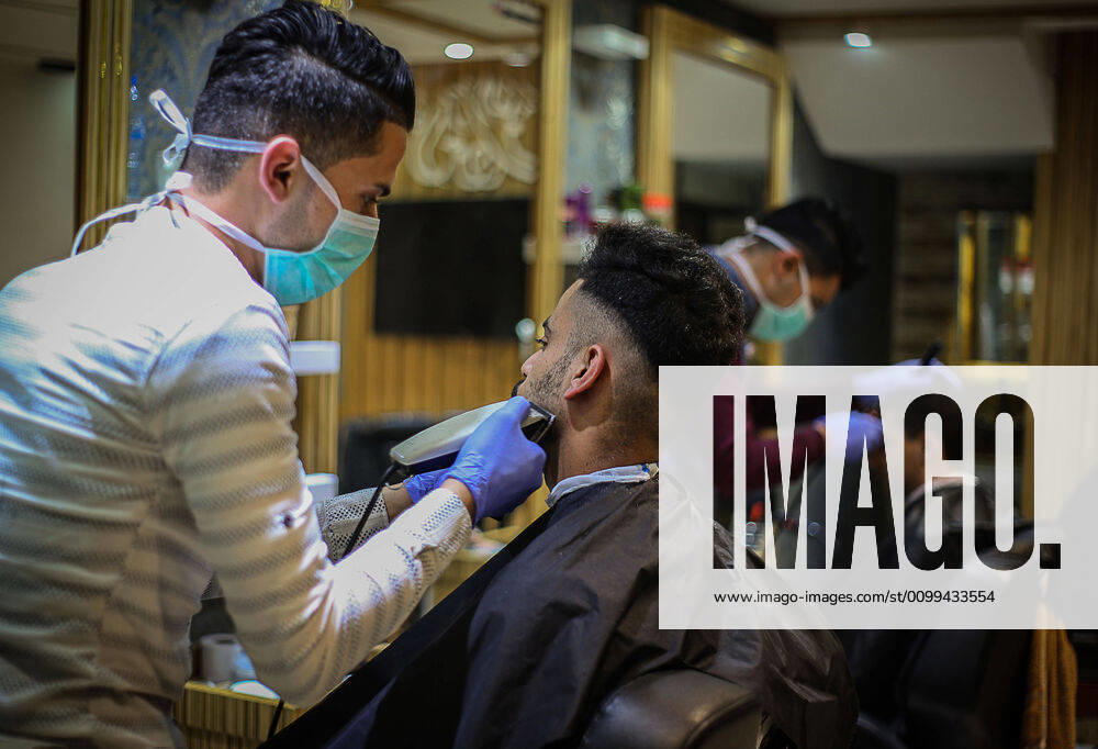 Daily Life at Barber in Southern Gaza Strip, Palestine amid Coronavirus Outbreak - 16 April 2020. A Palestinian barber wearing a face mask and a medical glove with his hand as a precautionary measure against Coronavirus (COVID-19), sterilizes his tools before cutting the customer s hair in Khan Yunis, southern Gaza Strip, Palestine, April 16, 2020. (Photo by Yousef Masoud INA Photo Agency imago images)