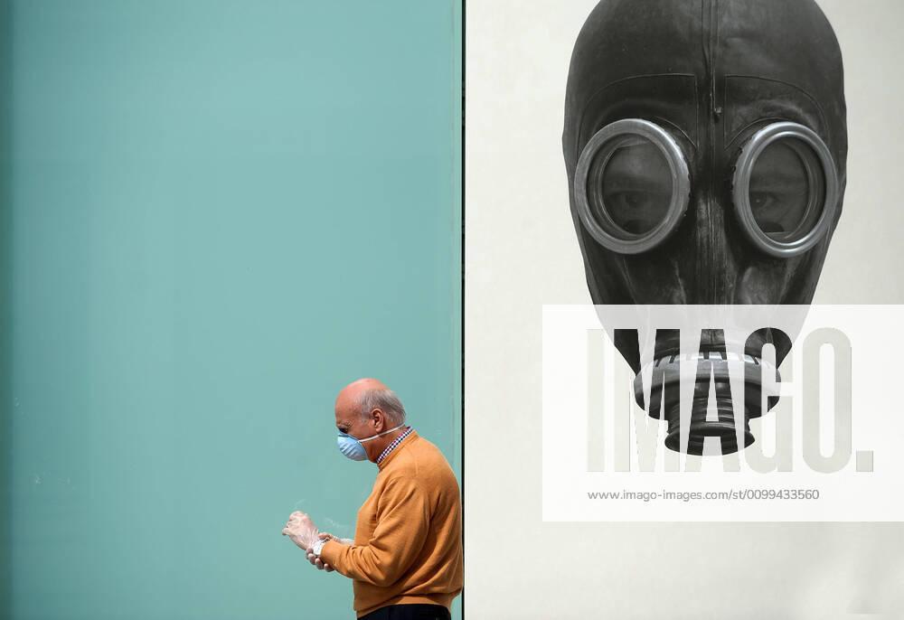A man wearing a face mask as a preventive measure, walking past a mural during the covid-19 crisis..Following the confinement decreed by the Spanish government and will extended until 10th May, people are confinement in their homes causing an exceptional situation of unusual urban scenes such as empty streets. Malaga Spain - ZUMAs197 20200416_zaa_s197_060