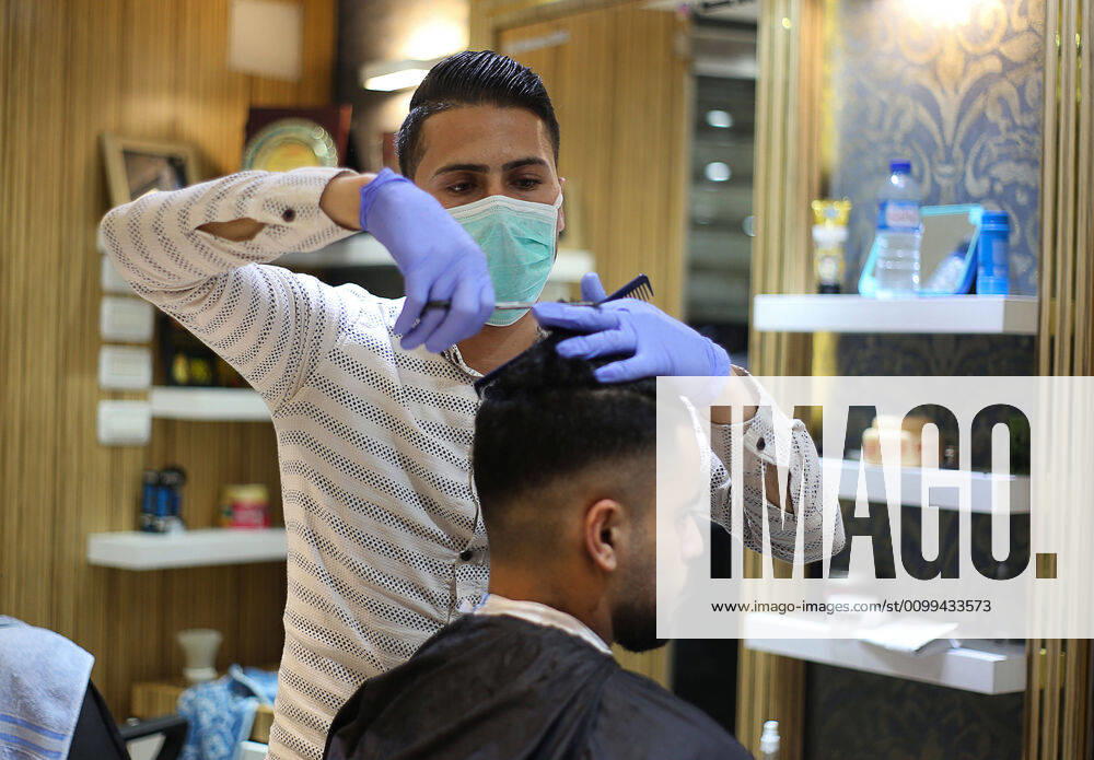 Daily Life at Barber in Southern Gaza Strip, Palestine amid Coronavirus Outbreak - 16 April 2020. A Palestinian barber wearing a face mask and a medical glove with his hand as a precautionary measure against Coronavirus (COVID-19), sterilizes his tools before cutting the customer s hair in Khan Yunis, southern Gaza Strip, Palestine, April 16, 2020. (Photo by Yousef Masoud INA Photo Agency imago images)