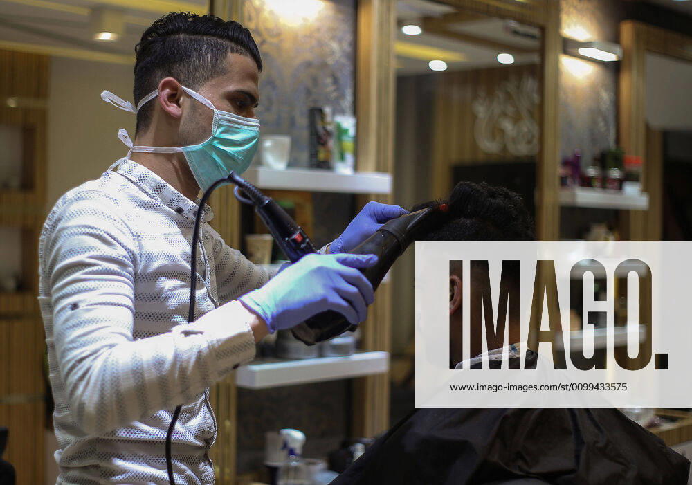Daily Life at Barber in Southern Gaza Strip, Palestine amid Coronavirus Outbreak - 16 April 2020. A Palestinian barber wearing a face mask and a medical glove with his hand as a precautionary measure against Coronavirus (COVID-19), sterilizes his tools before cutting the customer s hair in Khan Yunis, southern Gaza Strip, Palestine, April 16, 2020. (Photo by Yousef Masoud INA Photo Agency imago images)