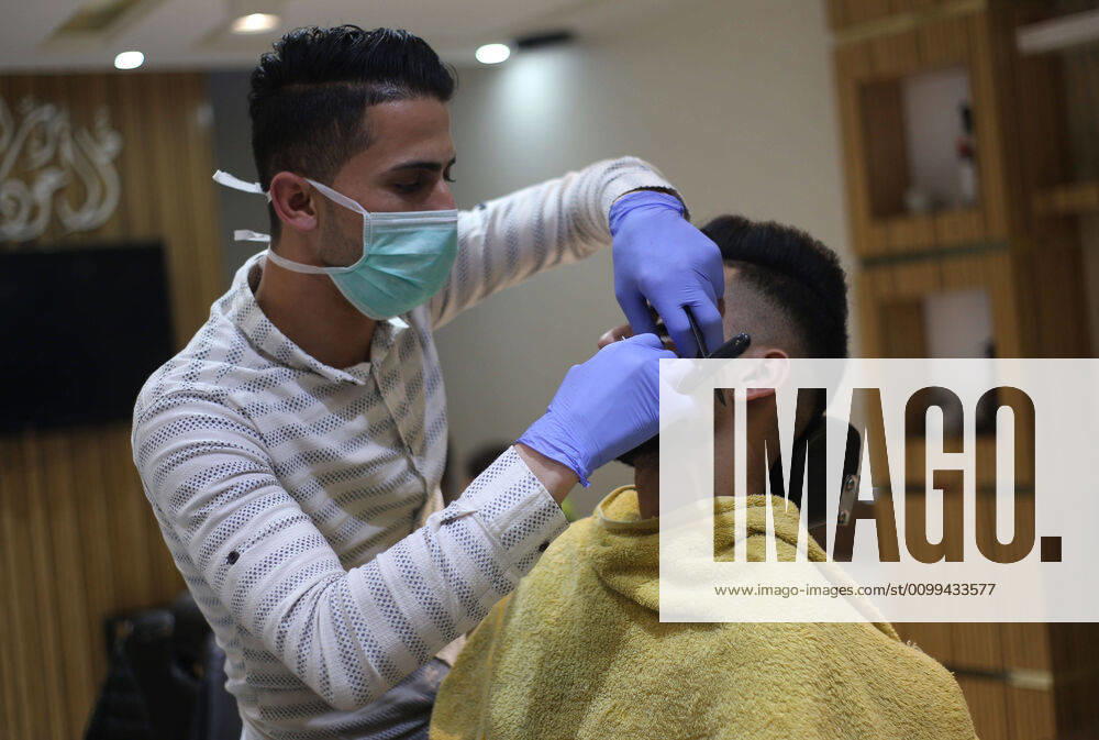 Daily Life at Barber in Southern Gaza Strip, Palestine amid Coronavirus Outbreak - 16 April 2020. A Palestinian barber wearing a face mask and a medical glove with his hand as a precautionary measure against Coronavirus (COVID-19), sterilizes his tools before cutting the customer s hair in Khan Yunis, southern Gaza Strip, Palestine, April 16, 2020. (Photo by Yousef Masoud INA Photo Agency imago images)