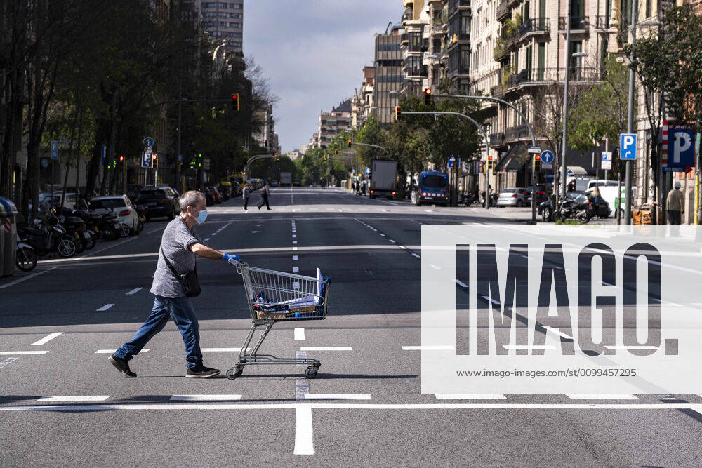 A man crosses the deserted Aragon street pushing a supermarket cart during confinement. Barcelona overcomes a month of home confinement and social distancing. It is already 34 days since March 15th when the Spanish Government decreed a state of emergency. Only essential services are functioning. Barcelona Spain - ZUMAs197 20200417_zaa_s197_061