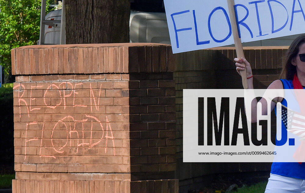 Reopen Florida is written on a wall with chalk as protesters demonstrate outside the Orange County Administration Building demanding the end of stay-at-home orders and the reopening of Florida businesses as the COVID-19 pandemic keeps thousands of people in their homes and out of work. Orlando United States - ZUMAs197 20200417_zaa_s197_228