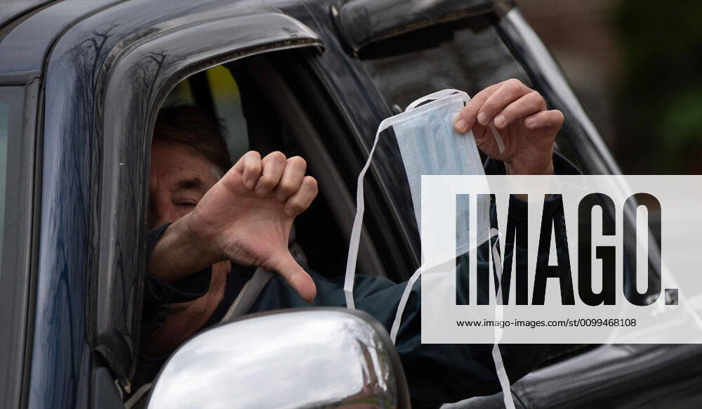A man holds a mask from his vehicle during a car protest to reopen Maryland and end the stay at home order imposed during the Coronavirus COVID-19 pandemic, near the state capitol building in Annapolis, Maryland on Saturday, April 18, 2020. Drivers circled Annapolis hoking their horns and calling for Gov. Larry Hogan (R-MD) to end the stay at home order. WAP20200418337 KEVINxDIETSCH