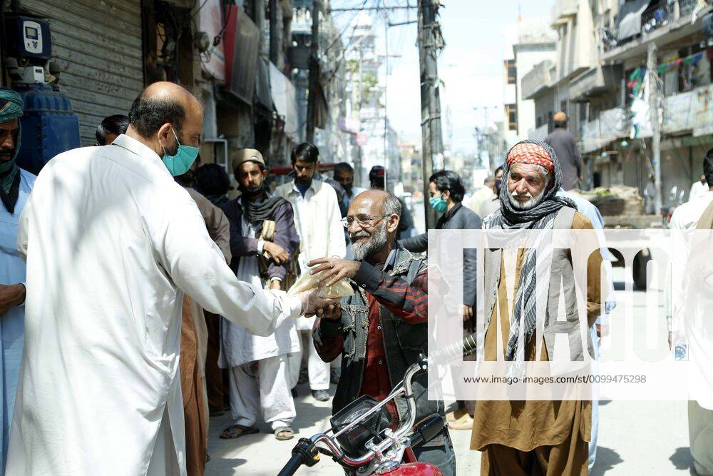(200419) -- RAWALPINDI, April 19, 2020 -- A man distributes charity food among people in Rawalpindi of eastern Pakistan s Punjab province on April 19, 2020. ) PAKISTAN-RAWALPINDI-COVID-19-DAILY LIFE AhmadxKamal