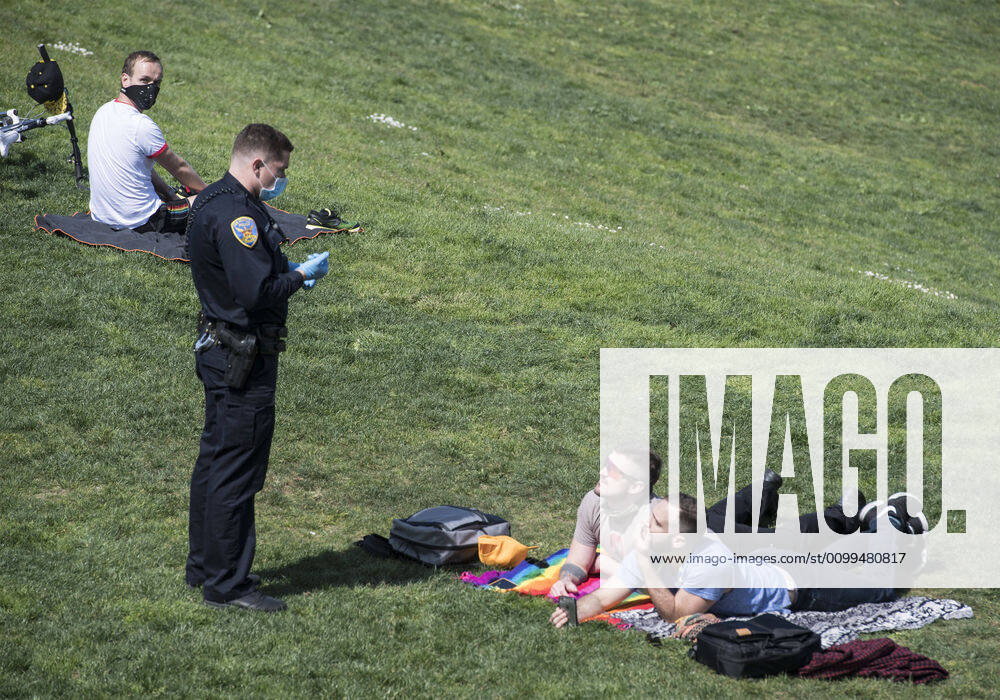 A police officer speaks with a couple on the grass at Delores Park in San Francisco on Sunday, April 19, 2020. San Francisco Mayor London Breed says that efective now, face masks must be worn outside the home to protect against coronavirus. SXP2020041902 TERRYxSCHMITT