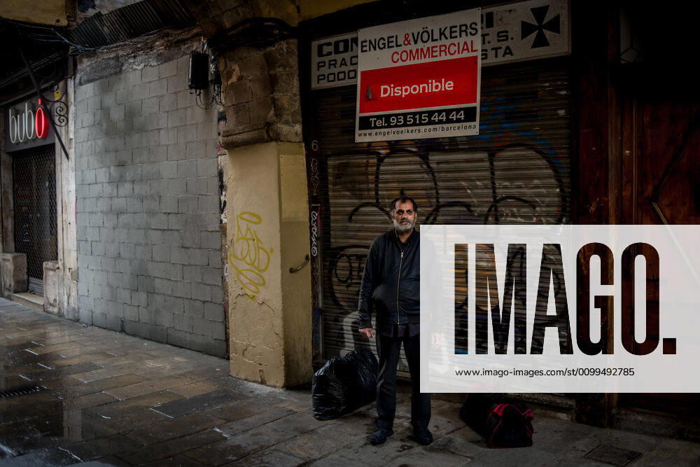 In Barcelona downtown a homeless man natural from India takes shelter form the rain under a porch close to a real estate company banner offering a renting place. Daily coronavirus deaths in Spain fall to 399, while confirmed cases now exceed 200,000. Barcelona Spain - ZUMAb137 20200420_zap_b137_013