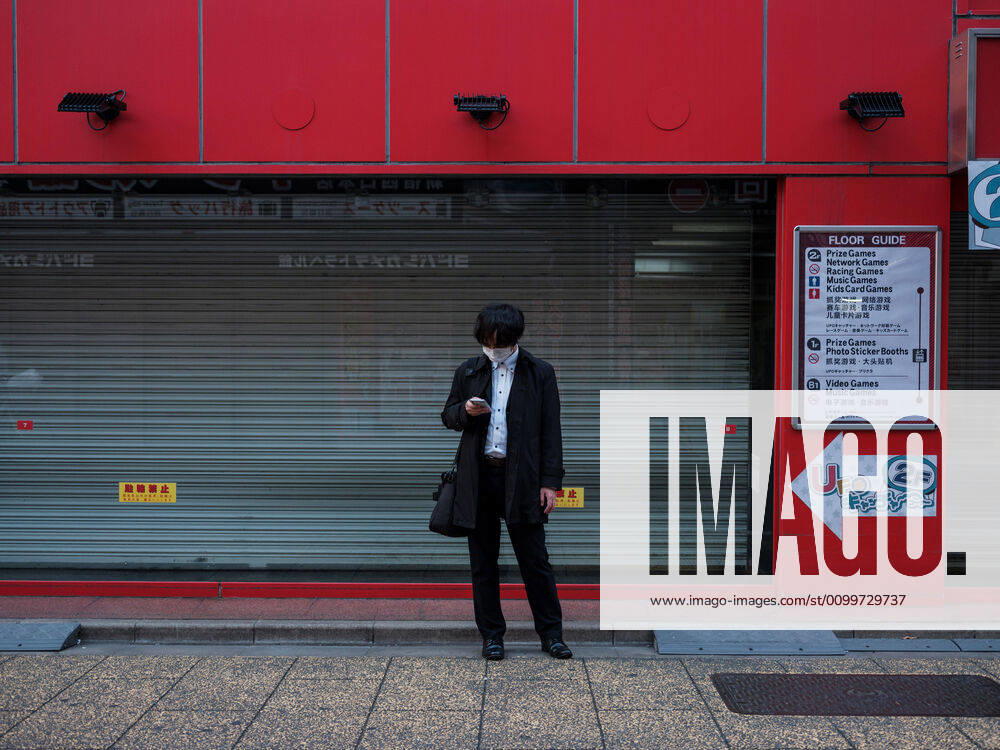 Coronavirus in Japan, Eindrücke aus Tokio A man wearing a mask looks as his smartphone in Shinjuku in Tokyo, Japan, 23 April 2020. Japanese Prime Minister Shinzo Abe extends state of emergency for Japan area for at least until second week of May on increase of coronavirus and COVID-19 infection cases. April 23, 2020 (125640964)