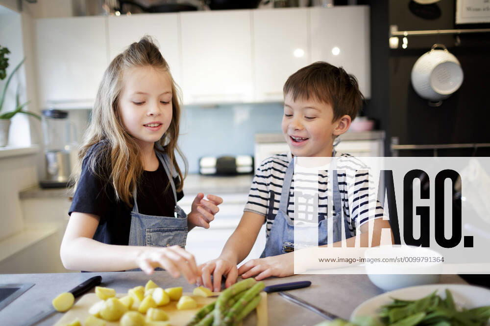 Portrait of girl and her little brother preparing vegetables in the kitchen model released Symbolfoto property released HMEF00869