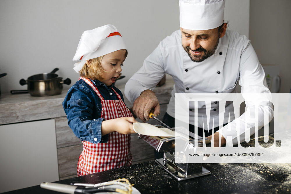 Father and daughter making homemade pasta with pasta machine in kitchen at home model released Symbolfoto property released JRFF04292