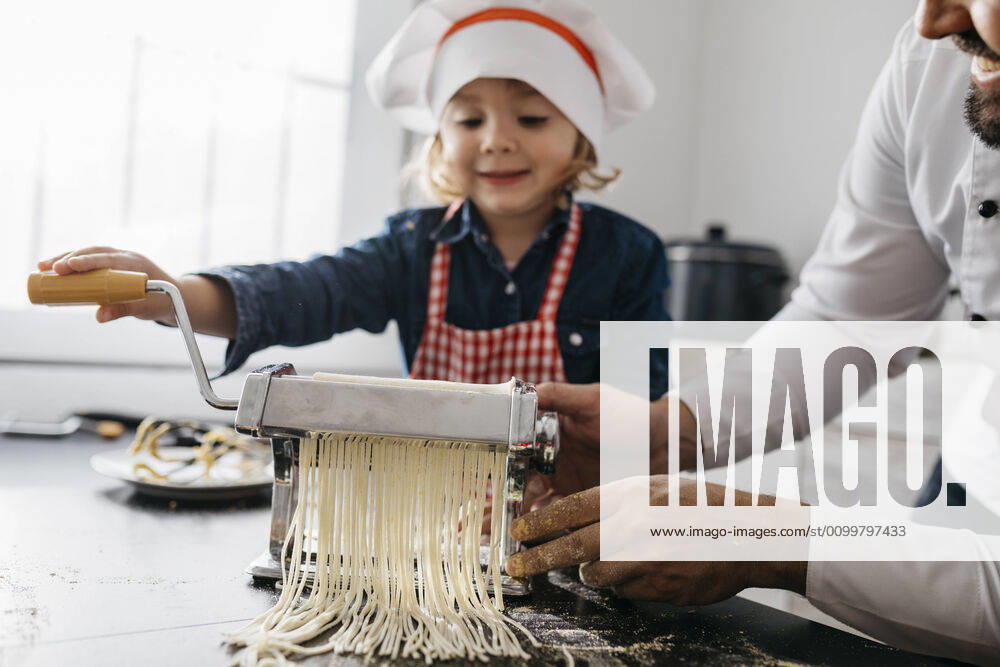 Father and daughter making homemade pasta with pasta machine in kitchen at home model released Symbolfoto property released JRFF04297