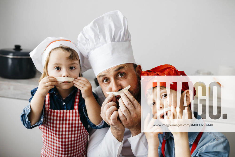 Playful father with two kids having fun while preparing homemade pasta in kitchen at home model released Symbolfoto property released JRFF04299