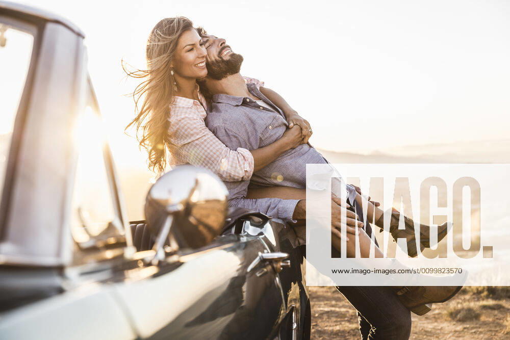 Happy affectionate couple at convertible car in the countryside at sunset model released Symbolfoto SDAHF00715