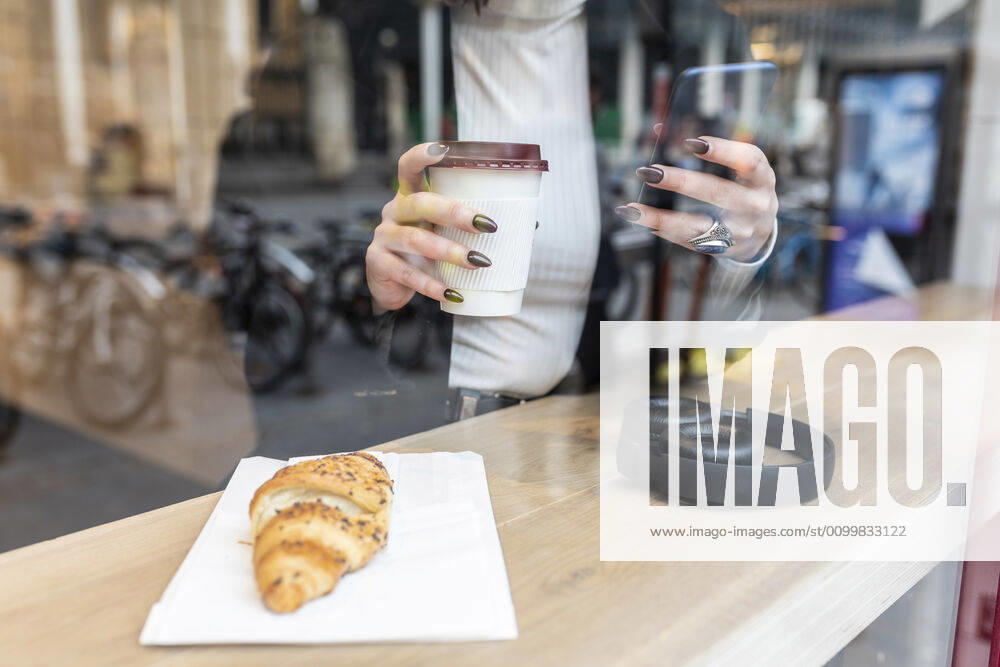 Close-up of businesswoman having a coffee break and using mobile phone at a cafe in the city model released Symbolfoto WPEF02779