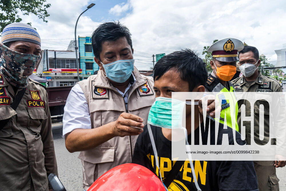 Coronavirus in Indonesien, Eindrücke aus Makasar April 24, 2020, Makassar, South Sulawesi, Indonesia: Police officers put masks on a motorbike driver who did not wear a mask when crossing the border in Makassar City, South Sulawesi Province, Makassar, Indonesia, to prevent Covid-19 transmission. Every citizen who does not wear a mask will be stopped and asked to return home. The curbing was carried out after the implementation of large-scale social restrictions in Makassar City and because the Covid-19 outbreak continued to increase in Indonesia. Makassar Indonesia - ZUMAb223 20200424_zip_b223_011