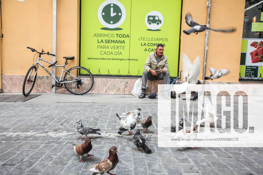 24 April 2020 (Malaga) a man feeds pigeons at the door of a supermarket during the coronavirus crisis - ZUMAc161 20200424_zap_c161_073