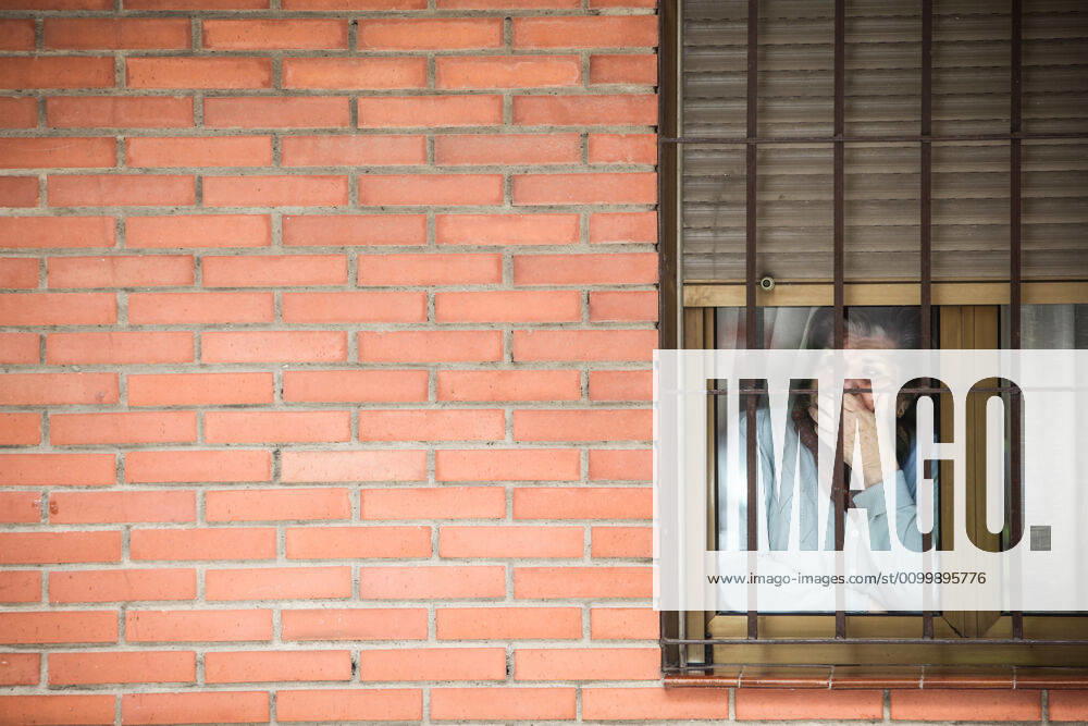 A woman looks out from behind a window during the Coronavirus crisis. Confinement is a safety measure for the entire Spanish population due to the coronavirus crisis. The Spanish government has enacted a strict stay-at-home order. Malaga Spain - ZUMAc161 20200424_zap_c161_063