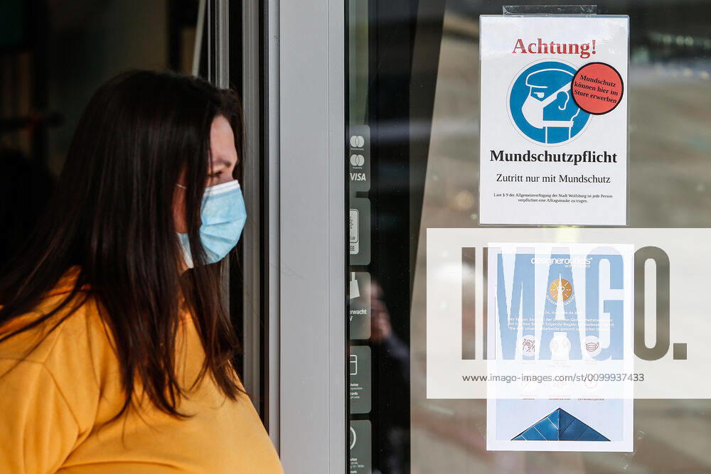 Consequences of the Corona Virus in Wolfsburg, an employee wearing a protective mask stands in front of a sign at Designer Outlet Wolfsburg DOW, Outlet Center In Wolfsburg, it is mandatory to wear a mask that covers mouth and nose in all shops and buses Wolfsburg