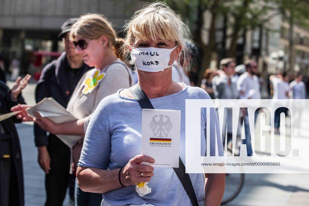 Muzzle written on a mask while holding a copy of the German Bill of Rights at a QAnon-like demo in Munich, Germany. Organized in Telegram chats by conspiratorial â€oeQuerfront†(cross-front) groups, the city of Munich, Germany saw numerous anti-state â€oeCorona Parties†as under mottos such as â€oeDemonstration fuer die Erhaltung der Grundrechte†(Demonstration for the Upholding of Basic Rights) and â€oeFuer unsere Freiheit, unsere Grundrechte und unsere Selbstbestimmung†(Demonstration for our Freedom, Basic Rights, and Self-Determination). Numerous right-extremists, Verfassungsschutz-monitored figures, QAnon fans, and AfD politicians were in attendance. The groups are of the belief that the anti-Coronavirus measures are power-grabs. Querfront groups a - ZUMAb160 20200425_zbp_b160_030