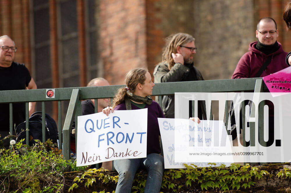 Lockdown immediately end demonstration on Südermarkt in Flensburg The Communication Centre for Democratic Resistance is organising a demonstration on 25 04 2020 in Flensburg on Südermarkt, city centre here counter-demonstrator, Hanna Poddig is sitting on the Südermarkt platform, holding up banners with the words Querfront nein Dank and Skpetisches Denken statt kruder Verschwörung