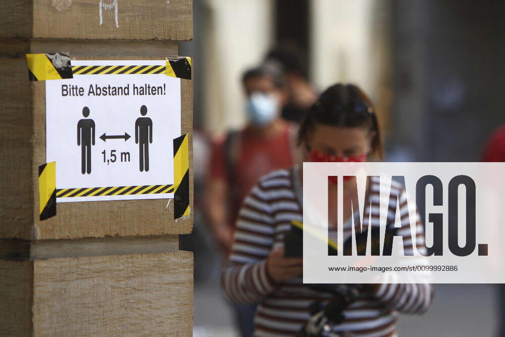 Safety measures for keeping a distance in the city centre of Karlsruhe Poster with an inscription please keep a distance of 1.50 metres and a reading woman wearing a breathing mask at a bookstore, Baden Württemberg, Germany