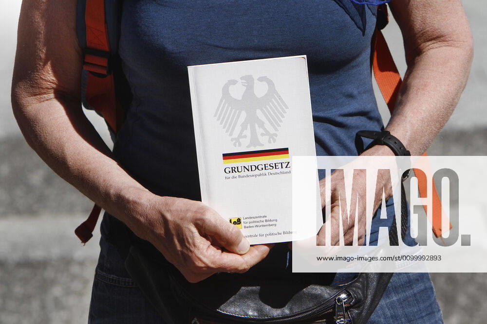 An approved demonstration, limited to a few participants, against the corona-related infection protection law and the associated restrictions on freedom took place in the city centre of Karlsruhe, Baden Württemberg, Germany Woman holding an issue of the Basic Law in front of her body