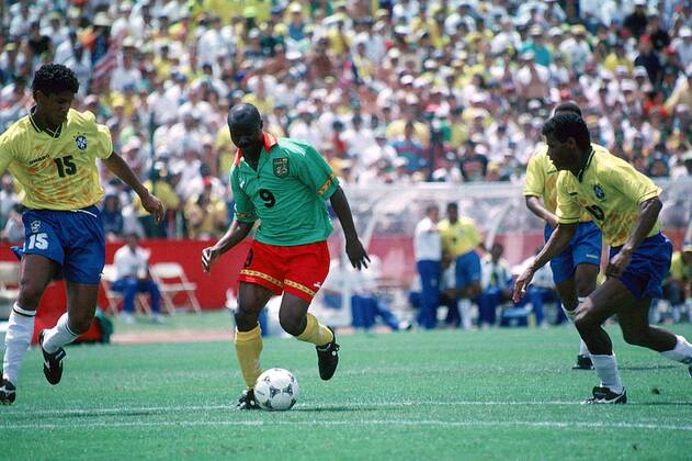 Der Kameruner Roger Milla mit Ball, verfolgt vom Brasilianer Marcio Santos (li.), re. Aldair Fußball WM Herren Länderspiel, Weltmeisterschaft 1994: Brasilien - Kamerun Gruppe San Francisco Dynamik,
