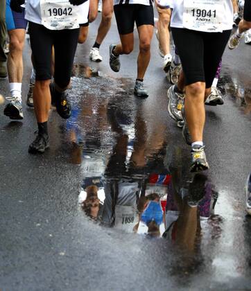 Marathonläufer spiegeln sich in den zahlreichen Pfützen, die sich auf der Straße gebildet haben Leichtathletik Köln-Marathon 2003, Stadtmarathon, Citymarathon, Marathonlauf, Langstrecke Gruppe Köln Dynamik,