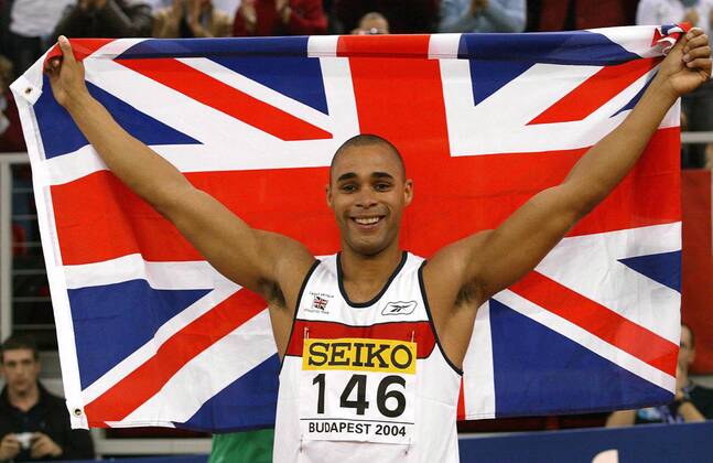 Weltmeister Jason Gardener (Großbritannien) jubelt mit dem Union Jack Leichtathletik WM Herren 10. IAAF Hallen-Weltmeisterschaft 2004, Hallenweltmeisterschaft, Halle, Indoor, Nationaltrikot Einzelbild Budapest Freude,