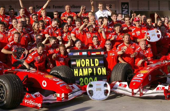 Nach dem GP von Ungarn in Budapest 2004 feiern Michael Schumacher (Deutschland, 3.v.re.), Rubens Barrichello (Brasilien, li.) und Teamchef Jean Todt (Frankreich, Mitte) im Kreise der Scuderia Ferrari den Gewinn der Konstrukteursweltmeisterschaft Motorsport Grand Prix Herren Großer Preis von Ungarn 2004, Formel 1 Weltmeisterschaft, F1, F, GP, WM, Weltmeister Totale Hungaroring, Teamwertung, Teamfoto Budapest, Konstrukteurswertung, Sieg, Sieger Begeisterung, Freude,