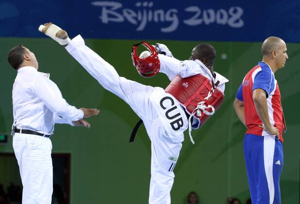 Olympia, Historie, Rückblick auf die Sommerspiele 2008 in Peking Angel Valodia Matos (Kuba) tritt Hauptkampfrichter Chakir Chelbat (Schweden, li.) mit voller Wucht - der Eklat mündete in einer lebenslangen Sperre für Matos -  Taekwondo OS Sommer Herren Olympische Spiele 2008, Sommerspiele, Tae Kwon Do, Taek Won, Taekwon, Klasse über 80kg o0 Aufmacher Gruppe o0 Kampfrichter, Schiri, Mattenrichter, Skandal, Peking o0 Sperre gesperrt lebenslang lebenslange, Dynamik, Kampf Spannung,