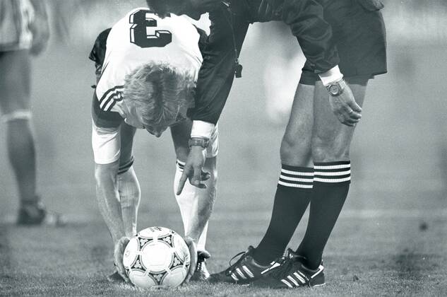 WM 1990, Hochspannung beim Finale in Rom - Andreas Brehme (BR Deutschland) legt sich besonders sorgfältig den Ball für den entscheidenden Elfmeter zurecht, denn Schiedsrichter Edgardo Codesal Mendez (Mexiko) will es ganz genau wissen o0 Gestik Körperteile Arm Hand Spannung BRD